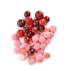 Heap of cranberry pills and berries on white background