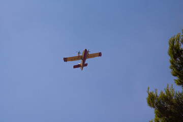 Canadair, Fire-Fighter Airplane, a twin-engined water bomber preparing to take water from sea near beach full of people and dump it on a forest fire. Summer wild fires in Greece. 