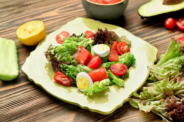 Tasty salad with salmon and fresh vegetables in plate on wooden background, closeup