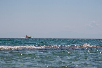 Canadair, Fire-Fighter Airplane, a twin-engined water bomber preparing to take water from sea near beach full of people and dump it on a forest fire. Summer wild fires in Greece. 