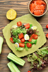 Tasty salad with salmon and fresh vegetables in plate on wooden background
