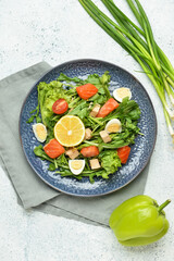 Tasty salad with salmon and vegetables in plate on light background
