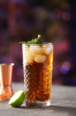 Glass of tasty Cuba Libre cocktail with mint on table in bar