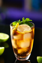 Glass of tasty Cuba Libre cocktail with mint on table in bar