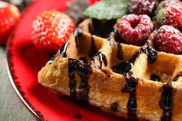 Plate of tasty Belgian Waffle with berries on table, closeup