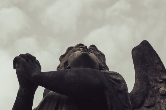 Looking up at a spooky gothic Victorian angel statue. Praying to the sky