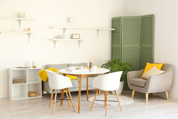 Interior of light dining room with sofa and armchair