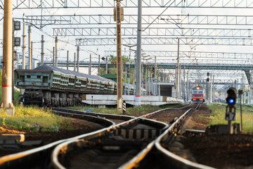 Fototapeta na wymiar Train station platform with railway tracks at sunset and commute electric train on background. Perspective of electrified high-speed railroad. Transportation concept. 