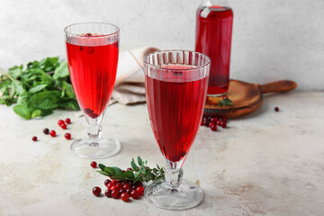 Glasses with healthy cranberry juice on light background