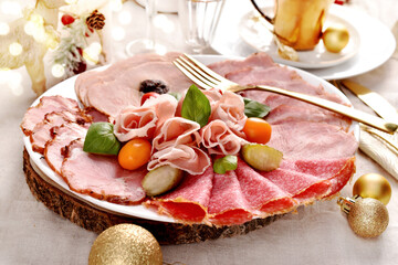Festive table with a platter of sliced prosciutto ham and cured meats for Christmas