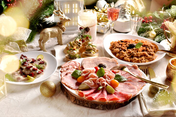 Festive table with a platter of sliced ham and cured meats herrings and sauerkraut stew for Christmas