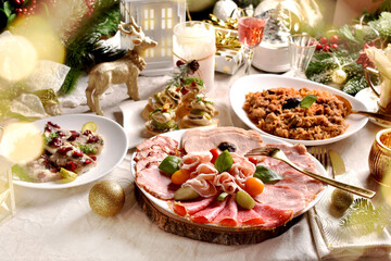 Festive table with a platter of sliced ham and cured meats herrings and sauerkraut stew for...