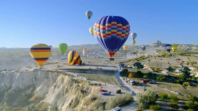 beautiful hot air balloons flies in bright blue cloudless sky. Dawn light hits balloon from one side, which is controlled by balloonist.