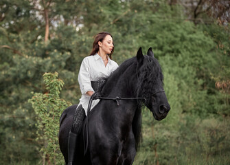 Beautiful long-haired girl riding a Friesian horse