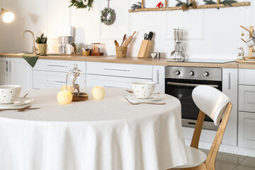 Dining table with beautiful setting in kitchen decorated for Christmas