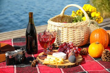 Tasty food with wine for romantic picnic near river on autumn day