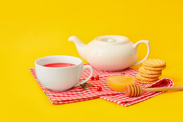 Cup of tasty lingonberry tea, honey and cookies on color background