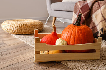 Wooden box with fresh pumpkins in room