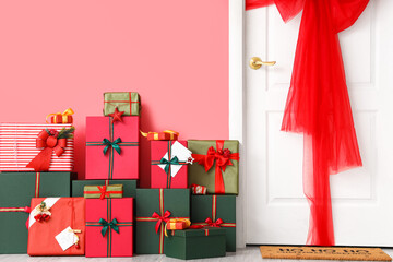 Decorated door and Christmas gifts near color wall