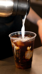 pouring cream into a cup of coffee