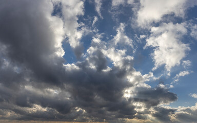 Fototapeta premium Sunlight through the clouds. Beautiful clouds in the blue sky. Evening autumn sky.