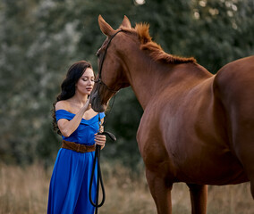 Obraz premium Beautiful long-haired girl in a blue dress with a red horse