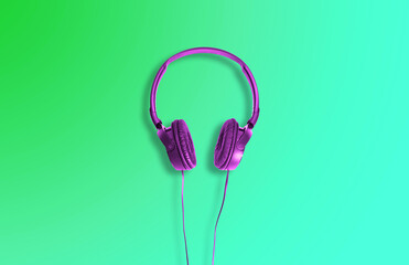 Computer headphones. Violet headphones on a green background. The concept of listening to music, creating audio, music. Computer work, abstraction and minimalist style.