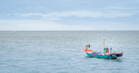 Obraz premium The small fisherman boat floating on the sea waiting for catching the fish and preparing to sell at the seafood market on the shore.