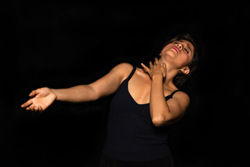 Portrait of a latina actress woman with indigenous features performing body movements on a black background