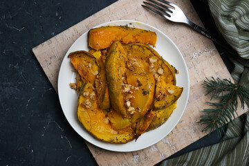 Plate of baked pumpkin sprinkled herbs and walnuts. 