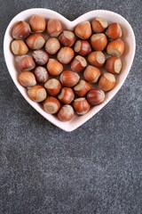 Hazelnut harvest. Nut in a pink heart plate on on slate background. Hazelnut on the slate.