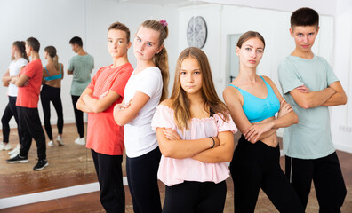 Fototapeta premium Cheerful teenage boys and girls having fun in choreography class, posing with female trainer..