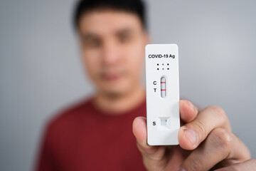man holding Coronavirus(Covid-19) positive test result with Antigen Rapid Test kit (ATK)