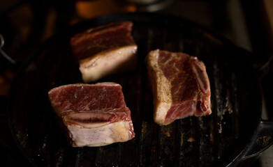 BEEF ON GRIDDLE CUT INTO CHUCKS COOKING ON A SLOW FIRE, WITH DARK FOOD TECHNIQUE AND SPACE FOR TEXT