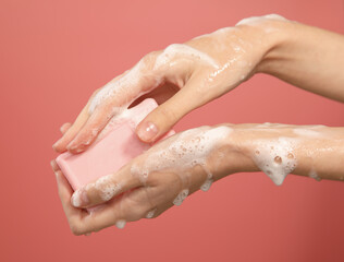 female hands washing with pink soap bar in foam isolated on pink background, close up - obrazy, fototapety, plakaty