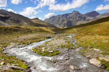 Hiking trail in Cogne valley, Aosta, Italy. Landscape of a wild mountain creek in the high walloon of Grauson.