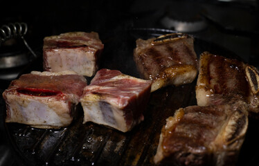 BEEF ON GRIDDLE CUT INTO CHUCKS COOKING ON A SLOW FIRE, WITH DARK FOOD TECHNIQUE AND SPACE FOR TEXT