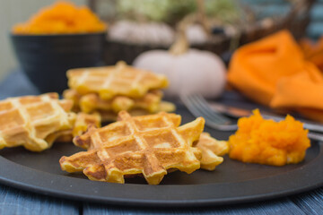 Viennese pumpkin waffles with pumpkin puree on a black metal plate.