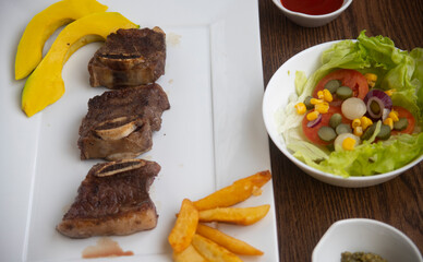 ROASTED BEEF, SERVED ON A WHITE PLATE AND LETTUCE, TOMATO AND CORN SALAD, ACCOMPANIED WITH FRENCH...
