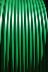 Grüne Erdkabel, aufgewickelt auf eine große hölzerne Kabeltrommel. Diese Kabel versorgen...