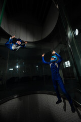 A man teaches a boy to fly in a wind tunnel. Lack of gravity.