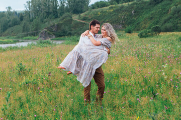 Happy romantic couple looking at each other on a field outdoors .