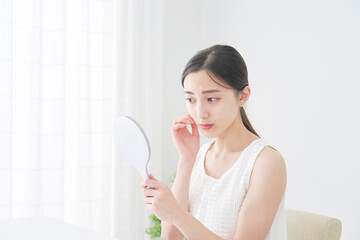 ハンドミラーで顔を見る女性