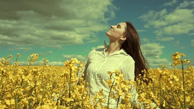 Happy beautiful young woman in rapeseed flowers field. Woman freedom. Woman power. Women rights.