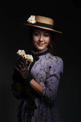 Close-up of a girl standing in a blue dress in the style of the 1900s, in a retro dress, hat and...
