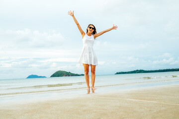 Fototapeta na wymiar Freedom happy woman with raised arms on the beach at sunny day