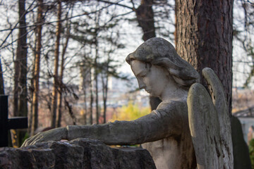 Fototapeta na wymiar Sculpture of an angel made of stone on a grave in a cemetery