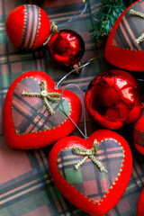 Christmas decorations for the Christmas tree. Balls and hearts of red color with a pattern of tartan