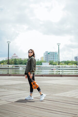 Playing Ukulele of Young Beautiful Asian Woman Wearing Jacket And Black Jeans Posing Outdoors