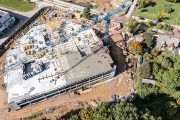 builders pouring wet concrete, using hose from concrete pumping machine into floor slab form. aerial view of construction site.